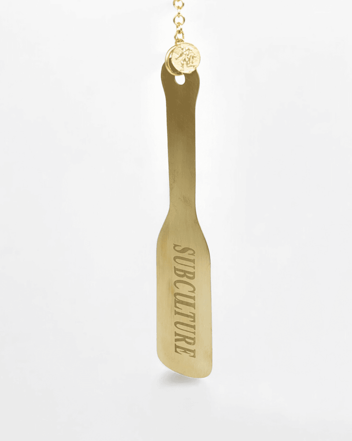 Spank it Metal Paddle Charm, metal impact toy by Subculture, worn view