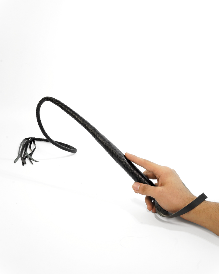 Scorpion Hunter leather whip in motion on white background — braided shaft curving through the air, close view of diamond-braid texture and leather falls at tip