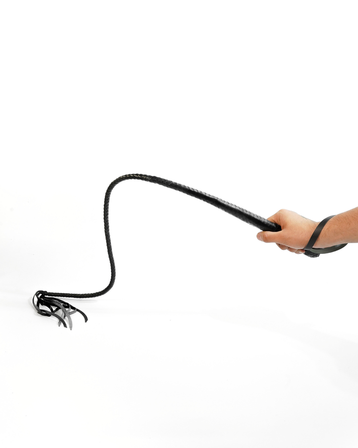 Scorpion Hunter leather whip held by handle on white background — braided shaft arcing downward to leather falls, showing grip and wrist loop