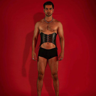 Rhiamon Unisex Leather Corset on male model, front view, black genuine leather with 4 stacked front buckles, red background, Leathersubculture