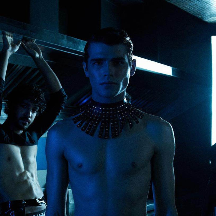 Subculture Maharaja Collar in black worn on model leaning forward - studded leather fringe collar in moody blue industrial editorial setting, Leathersubculture